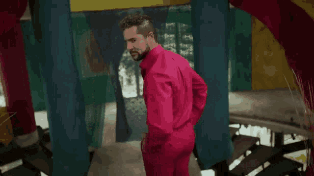 a man in a pink suit stands in a room