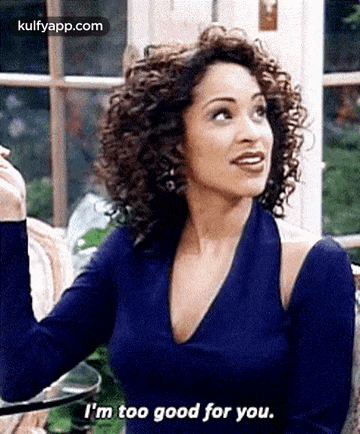 a woman with curly hair is sitting at a table and talking to someone .