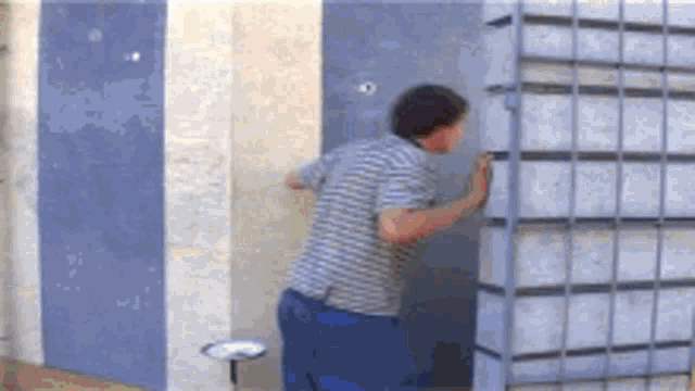 a man in a striped shirt is looking through a door