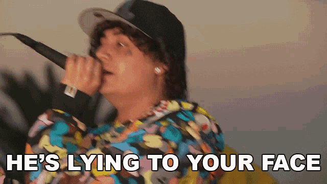 a man is singing into a microphone with the words he 's lying to your face behind him