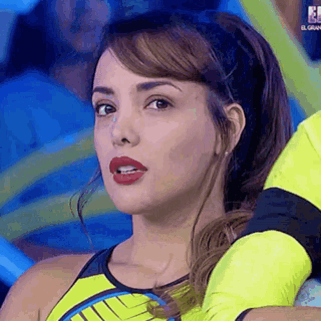 a close up of a woman wearing a yellow tank top and a headband looking at the camera .
