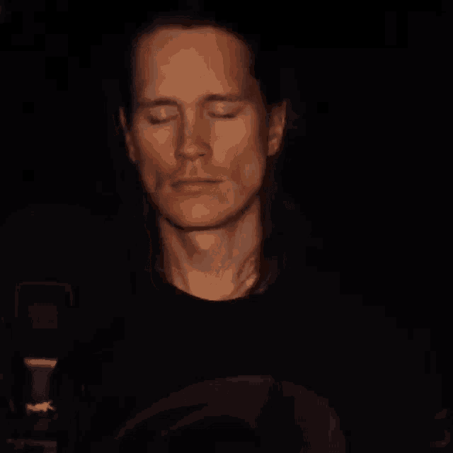 a man with his eyes closed in a dark room .