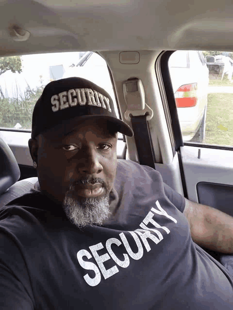 a man in a car wearing a security hat and a security shirt