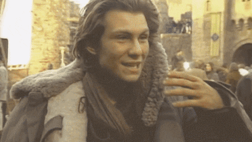 a man with long hair is wearing a fur jacket