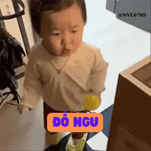 a baby is standing in a room with a yellow ball and a sign that says do ngu .