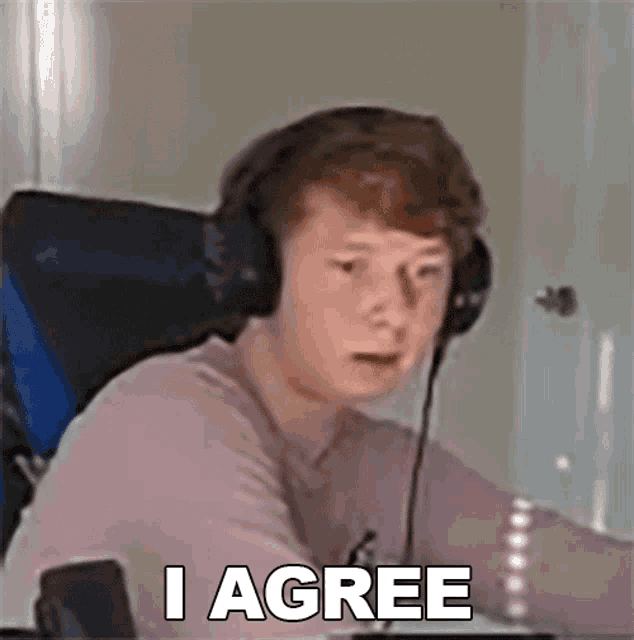 a young man wearing headphones is sitting in a chair and making a face .
