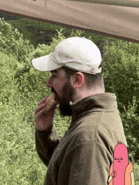 a man with a beard is eating a hot dog