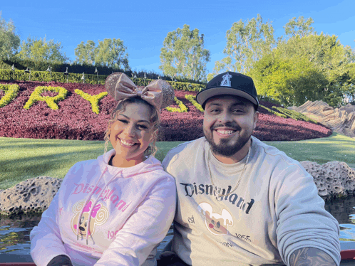 a man wearing a disneyland shirt sits next to a woman