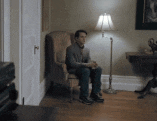 a man is sitting in a chair in a room with a lamp
