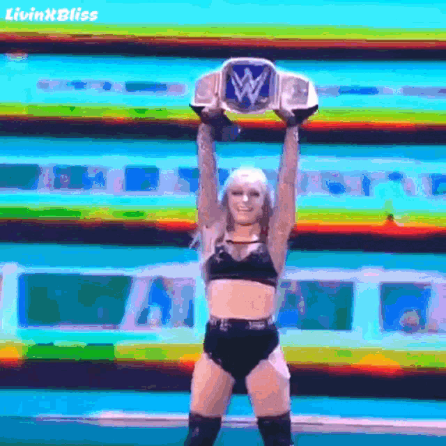 a female wrestler is holding a wwe championship belt in her hands