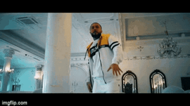 a man with a beard is dancing in a room with a chandelier