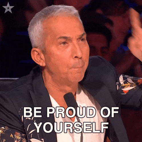 a man in a suit says be proud of yourself while holding a microphone
