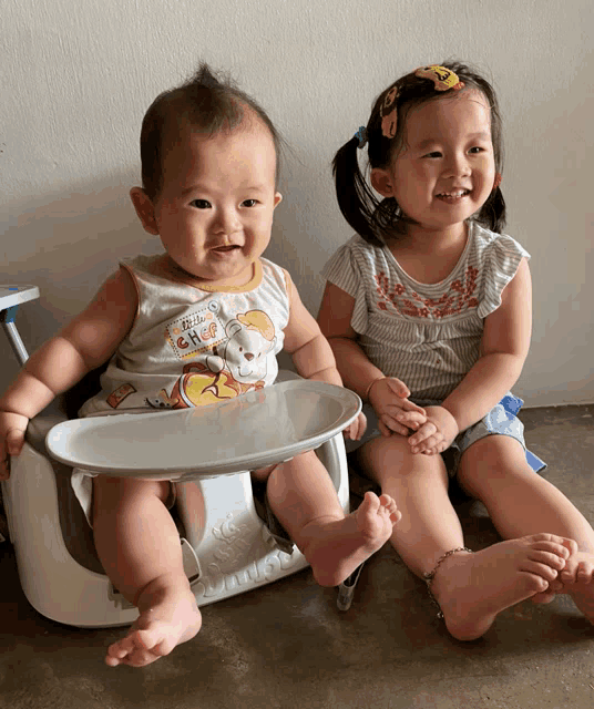 a baby wearing a winnie the pooh outfit sits next to a little girl