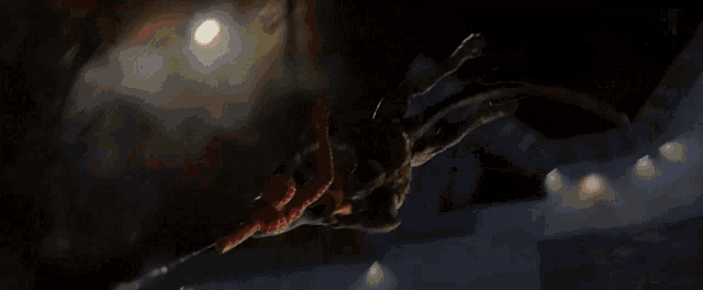 a man in a superhero costume is hanging from a crane at night