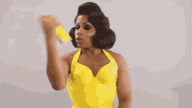 a woman in a yellow dress is holding a yellow spray bottle .