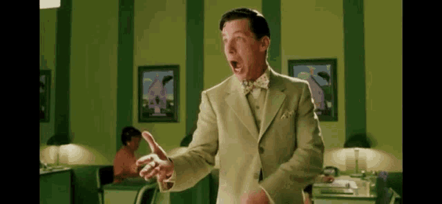 a man in a suit and bow tie is standing in an office .