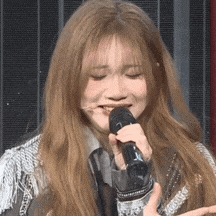 a woman is singing into a microphone while making a funny face .