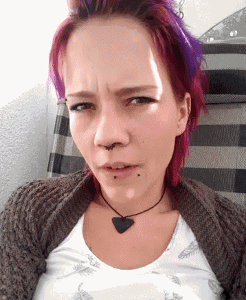 a woman with purple hair and a nose ring is sitting in a chair