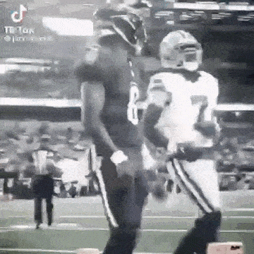 a black and white photo of two football players standing on a field .