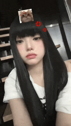 a girl with long black hair has a picture of a cat on her forehead