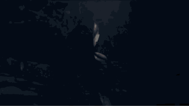 a woman in a black tank top and white bra is sitting in the dark .