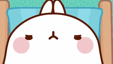 a cartoon rabbit is laying in a bed with a blue pillow and a sad face .