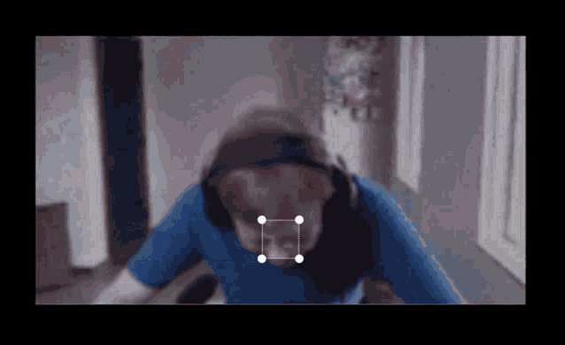 a man wearing headphones and a blue shirt is sitting in front of a computer screen .