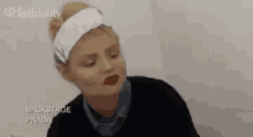 a woman wearing a headband and red lipstick is making a face .
