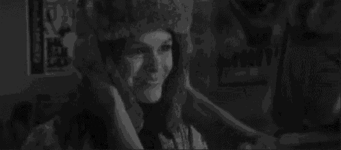a black and white photo of a man wearing a fur hat and a woman wearing a fur hat .