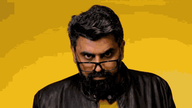 a man with a beard and glasses is wearing a black leather jacket