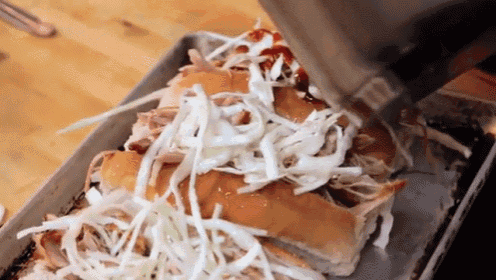 a pulled pork sandwich with coleslaw and ketchup being poured on it