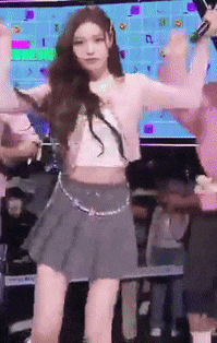 a woman in a crop top and a pleated skirt is dancing