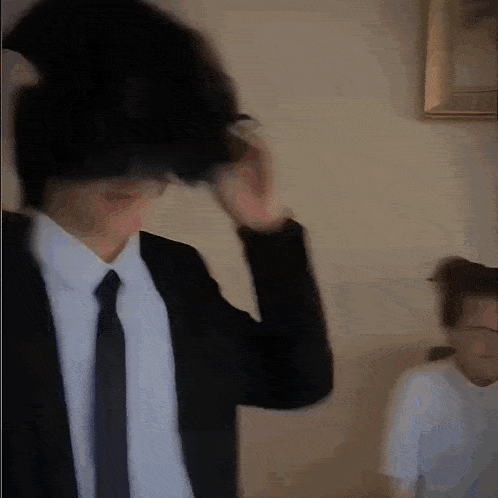 a man in a suit and tie adjusts his hair