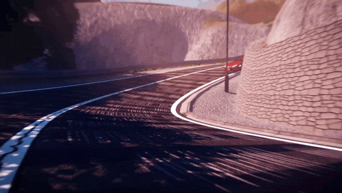 a car is driving down a road with a stone wall on the side