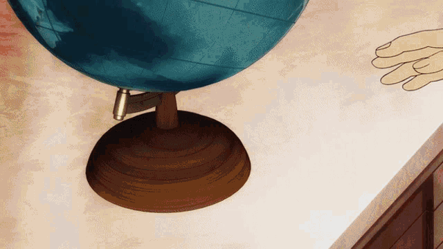 a blue globe sits on a table with a drawing of a hand behind it