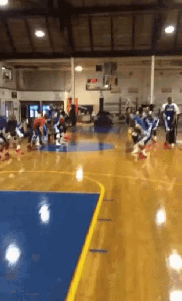 a group of people are playing basketball on a court with a basketball hoop in the background