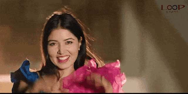 a woman in a pink dress is smiling in front of a loop video ad
