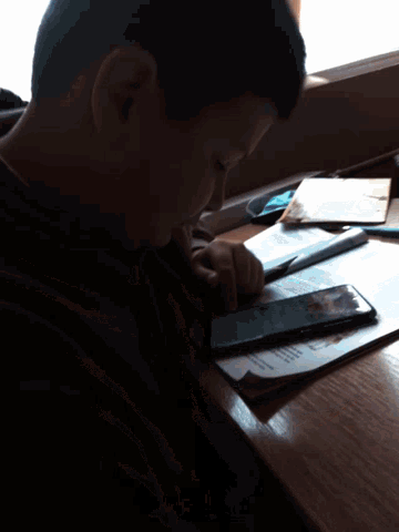 a young boy sits at a desk looking at a tablet