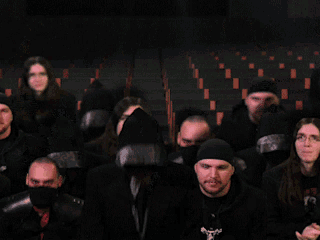 a group of people are standing in a dark room and one of them has a hood on