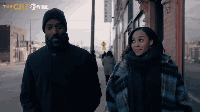 a man and a woman are walking down a sidewalk in front of a showtime building