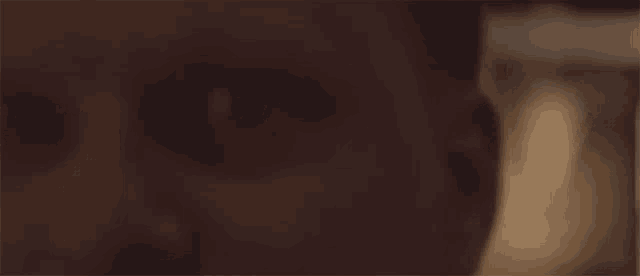 a close up of a person 's face in a dark room with a blurred background .