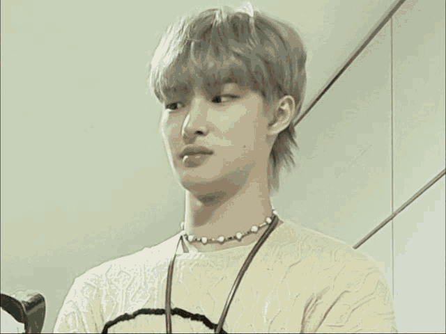 a young man wearing a pearl necklace and a white shirt