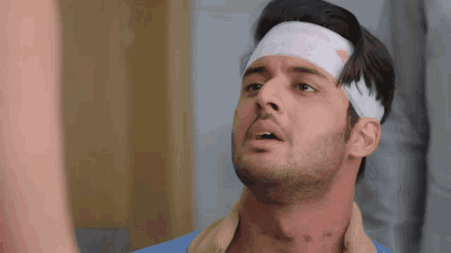 a man with a bandage on his head is in a hospital room .