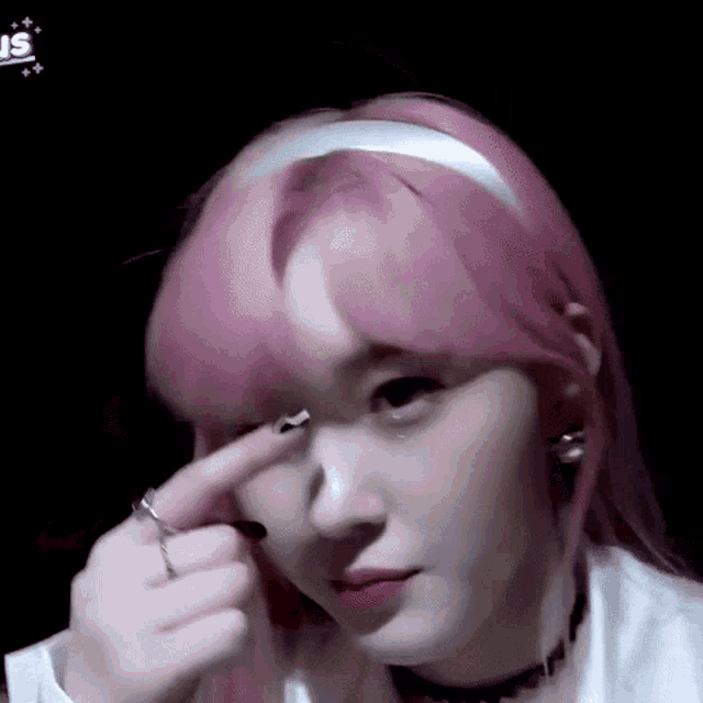 a close up of a woman with pink hair making a face .