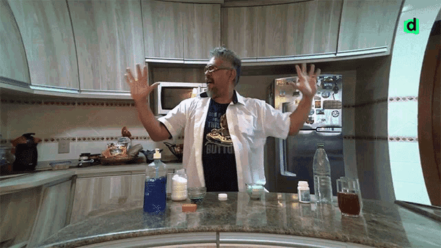 a man in a kitchen wearing a shirt that says ' button ' on it