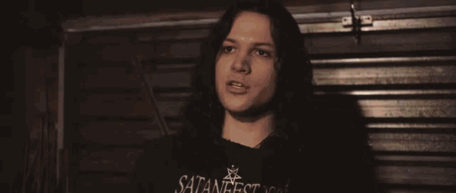 a man with long hair stands in front of a sign that says " ehrgasm "