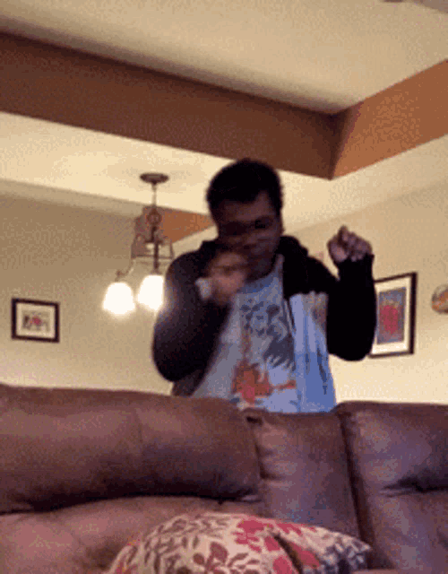 a man in a t-shirt with a dragon on it is standing on a couch