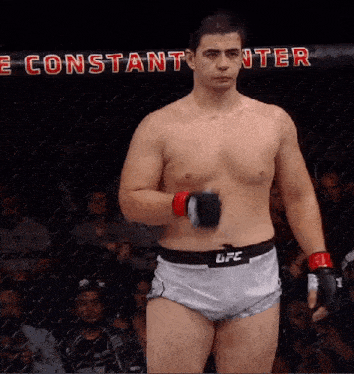 a man in a ufc belt stands in a boxing cage