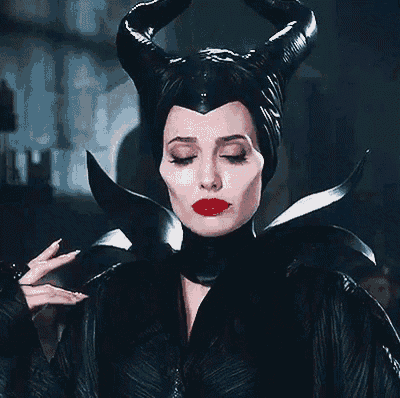 a woman in a black costume with horns and red lips is making a face .