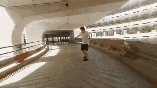 a man in a white shirt and black shorts is doing a trick in a tunnel